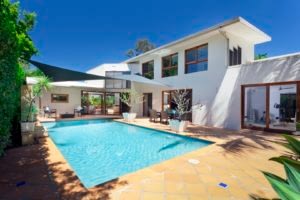 Rectangular Swimming Pool In Back Of A Large White House