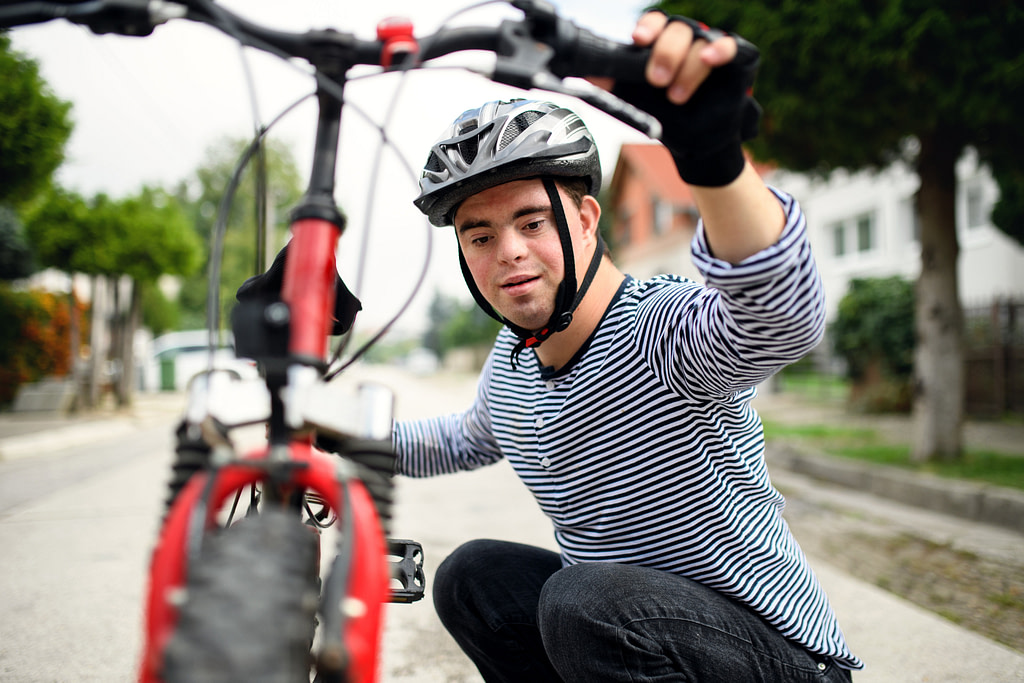 Portrait Of Down Syndrome Adult Man With Bicycle Standing Outdoors On Street.