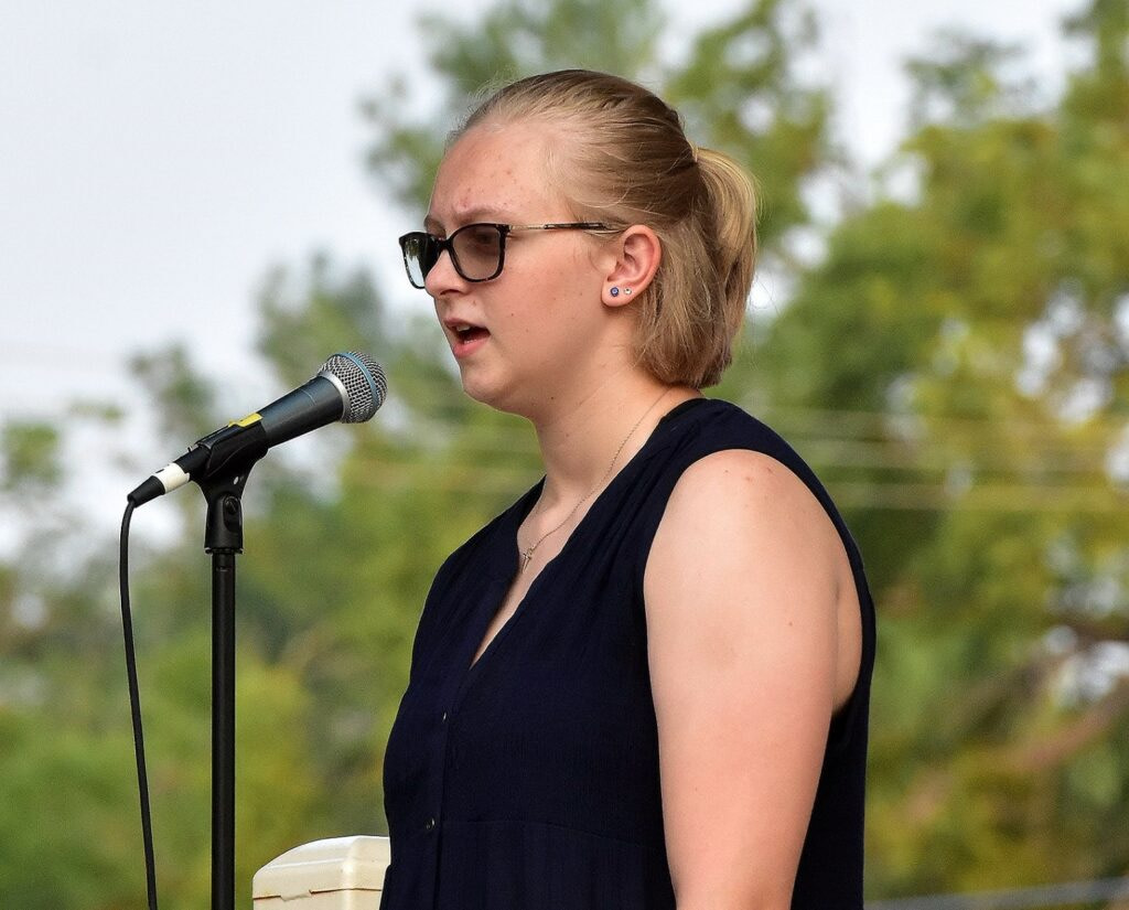 a woman wearing sunglasses and singing into a microphone