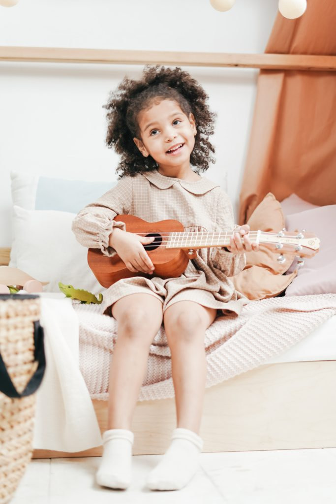 A young girl playing a ukulele.