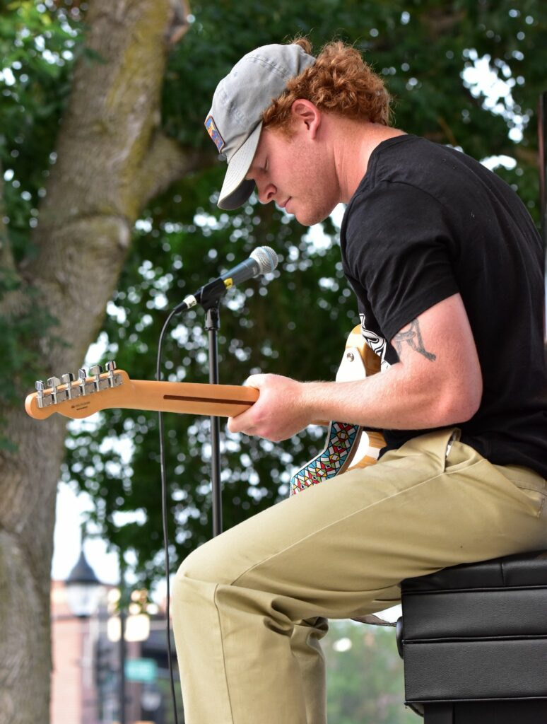 A college-age man playing electric guitar.