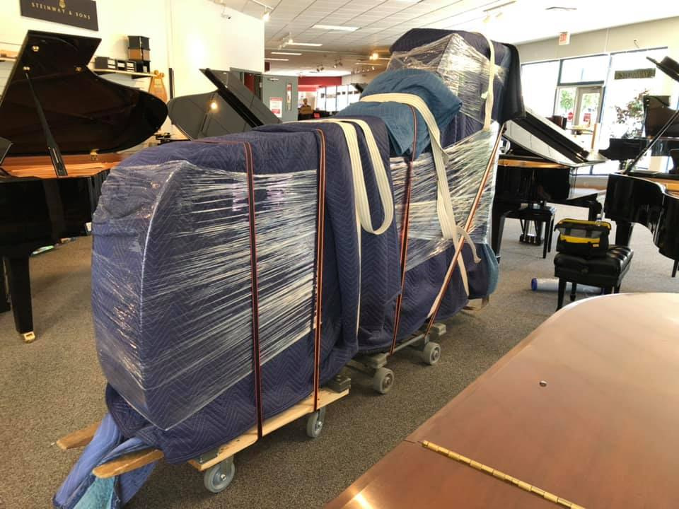 A piano, wrapped up in bedsheets and plastic ready for moving.
