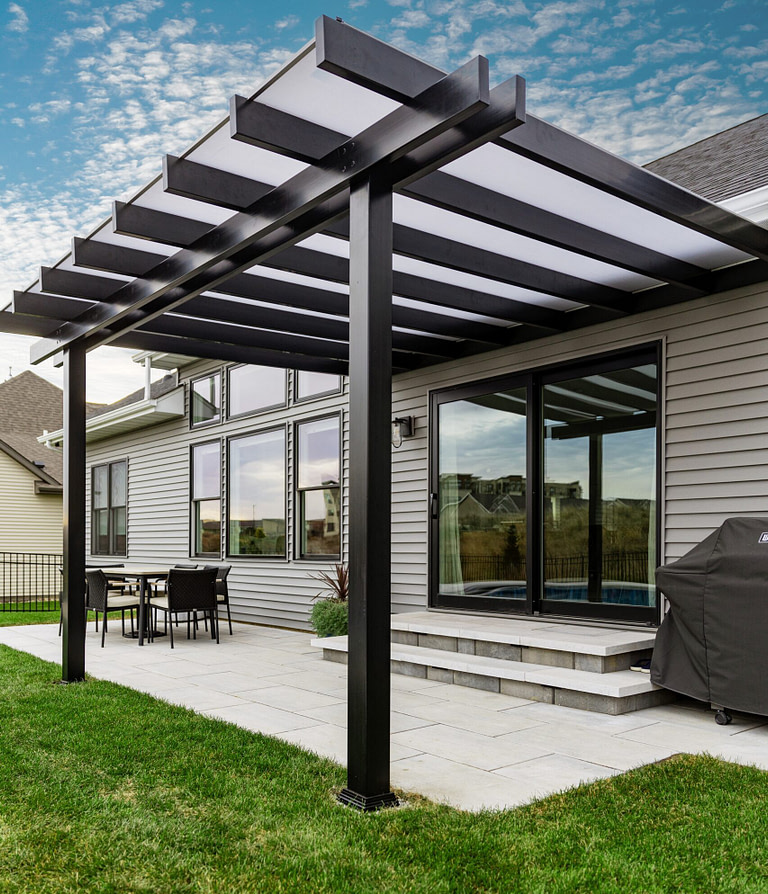 Black covered pergola with white polycarbonate roof over a patio