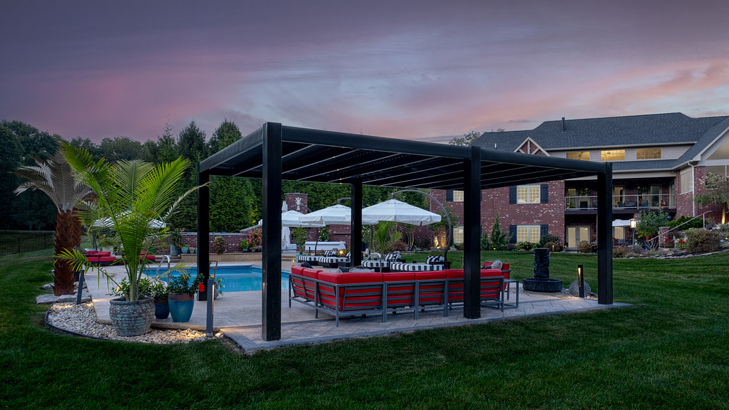 A black vinyl pergola at dusk next to a pool