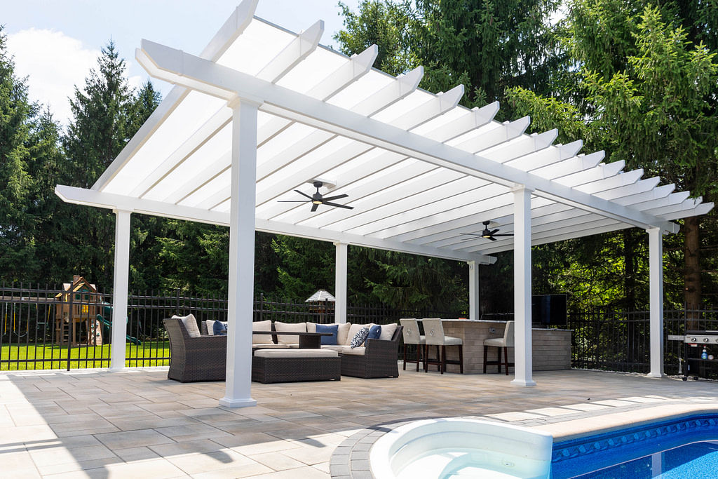 pool side patio with large white covered pergola structure over a outdoor seating area and outdoor bar area