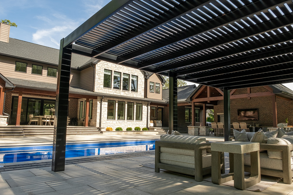 A view from under a black vinyl pergola over a poolside patio