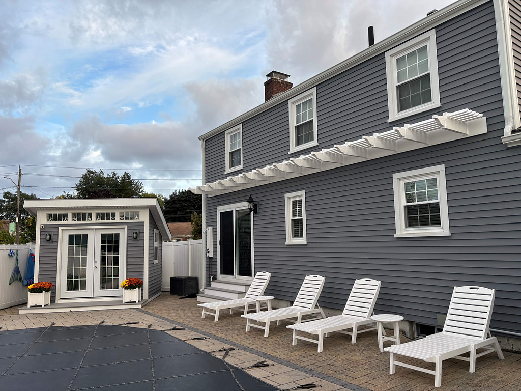 accent wall pergola across the back of a gray blue house