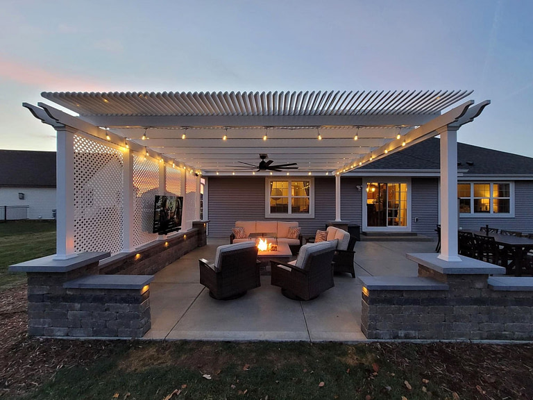 Outdoor Shade pergola at dusk with outdoor fan, outdoor tv, and privacy wall