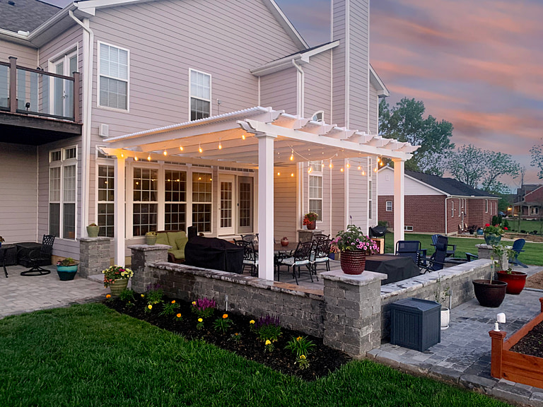 White pergola over patio at dusk with string lights