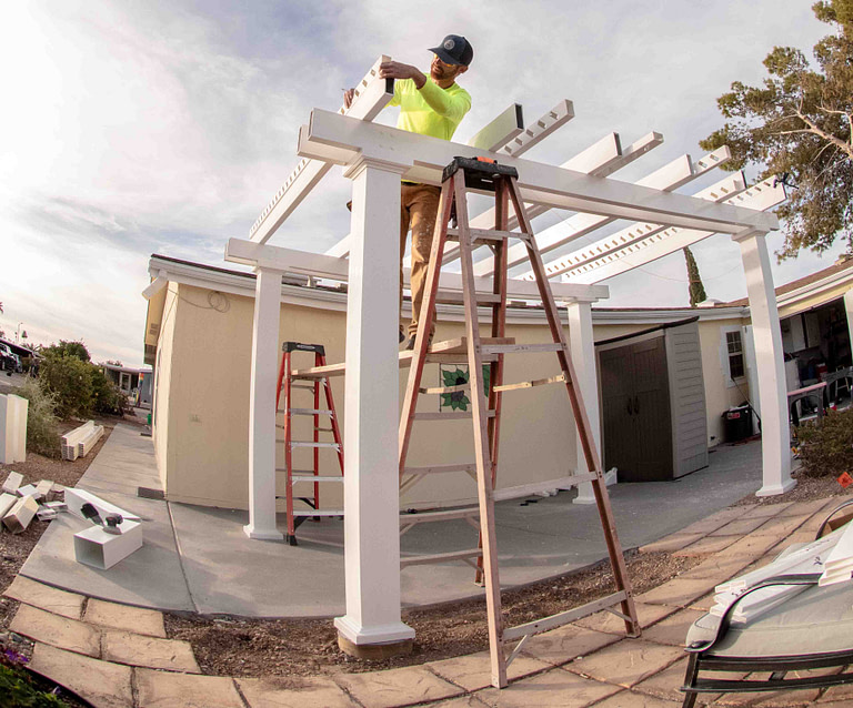 a contractor is building a white heartland pergola on a patio