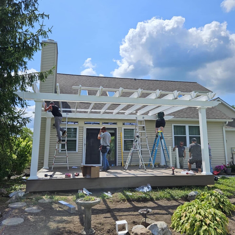 a contracting crew is building a white heartland pergola on a deck