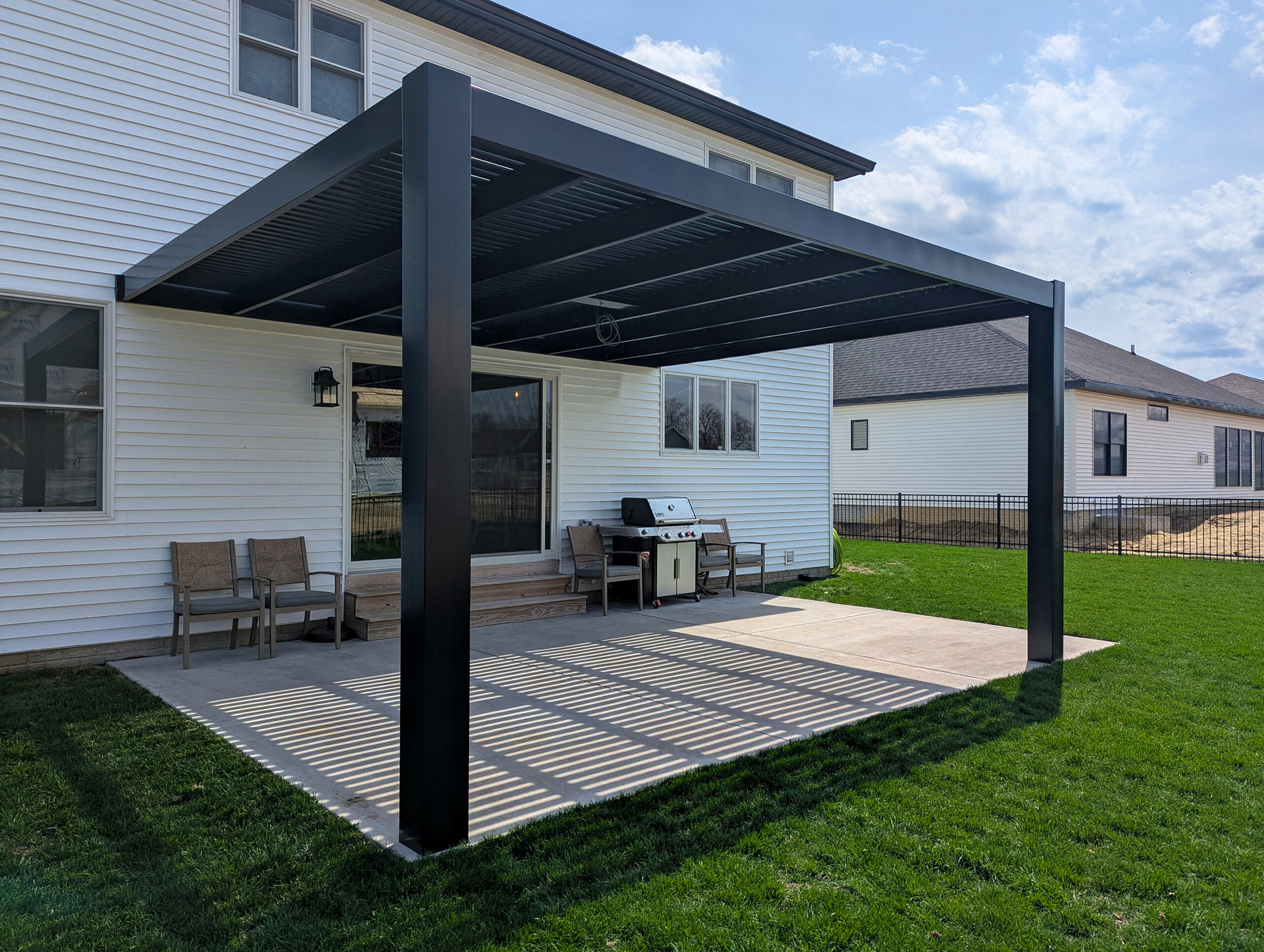 Elements rain proof pergola with solid roof panels installed over a patio