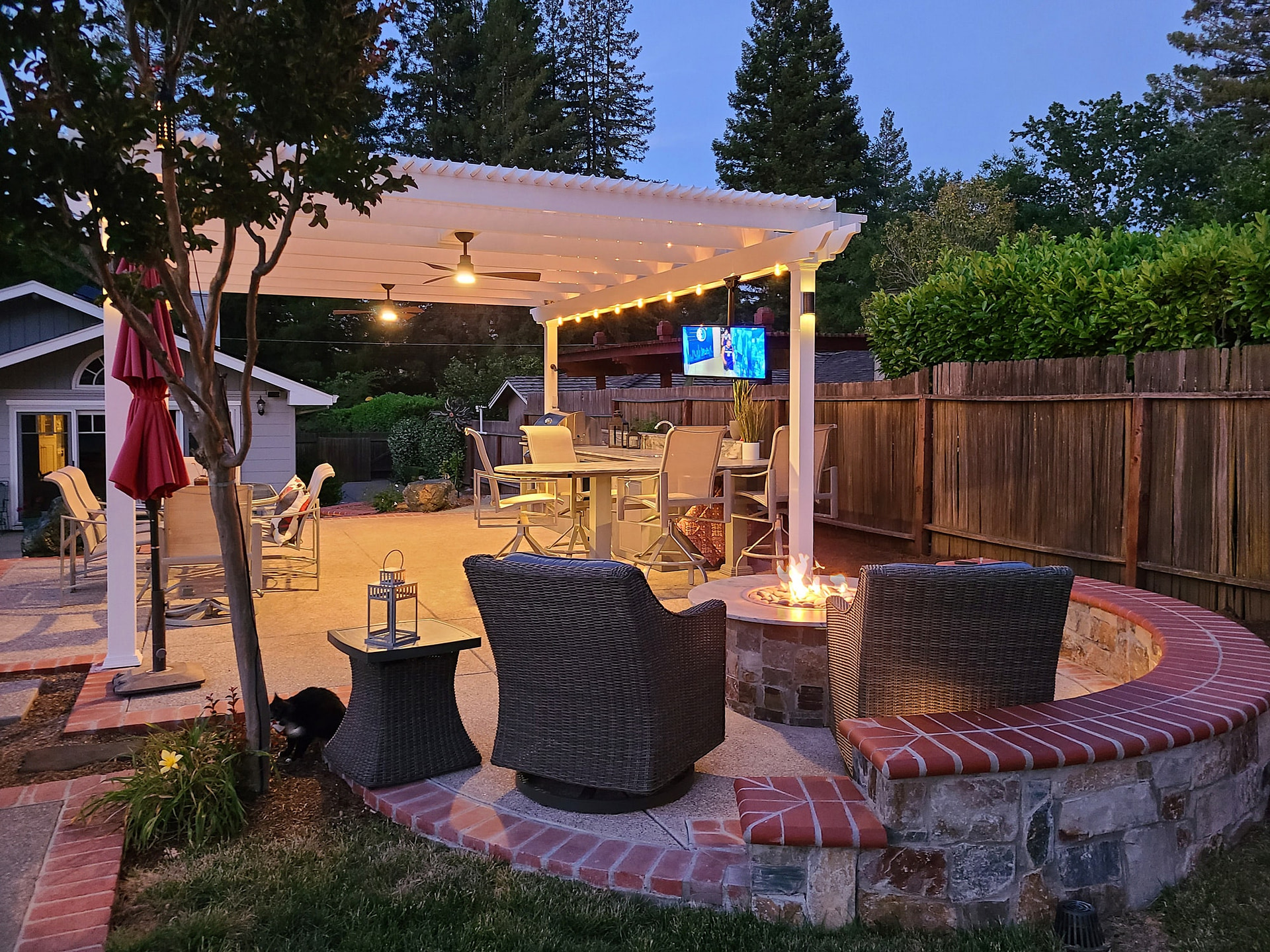 outdoor pergola with fans and outdoor tv at night lit up over patio