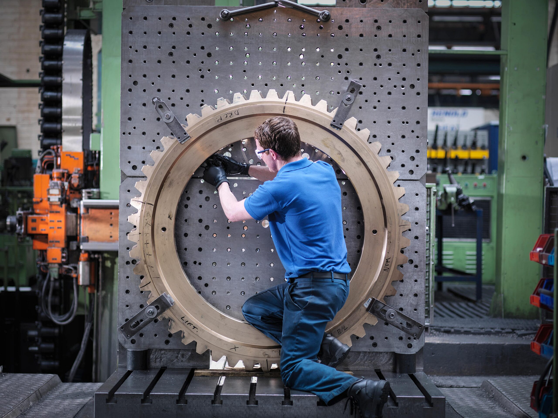 Engineer fitting gear wheel on lathe in engineering factory