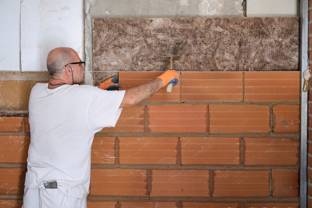 a man standing in front of a brick wall