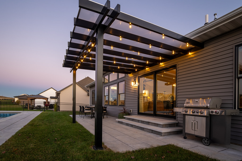 Black patio cover with white polycarbonate roof over a patio at dusk