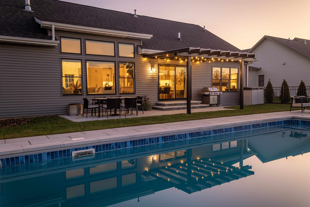 Black patio cover with white polycarbonate roof over a patio at dusk