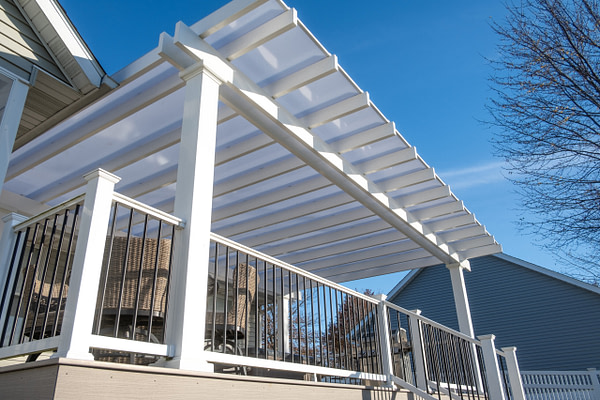 White vinyl rain proof pergola with white polycarbonate roof over an outdoor deck.