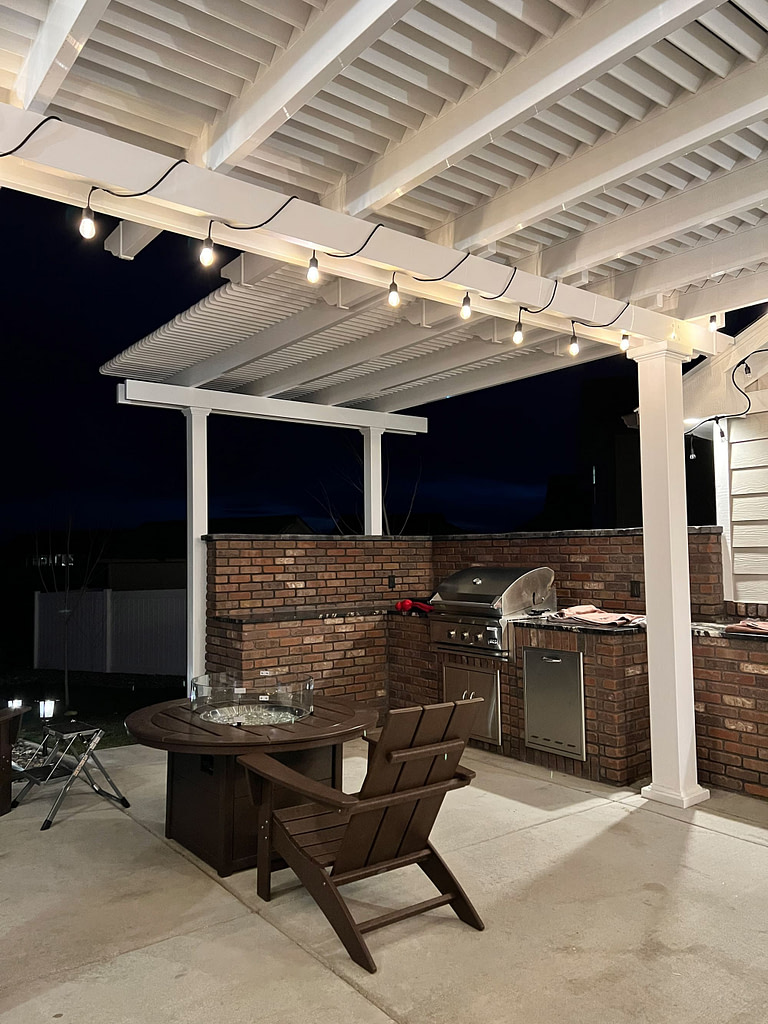 L shaped pergola at night lit up with string lights