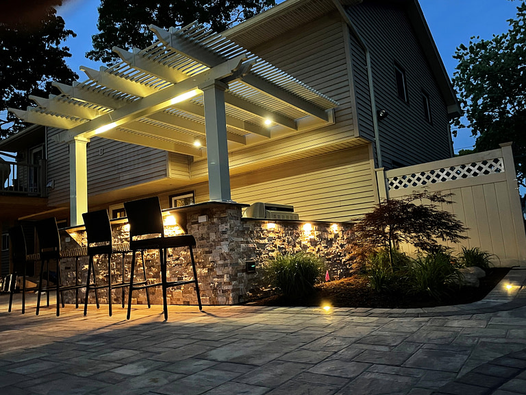 Bar top attached pergola at night lit up with various lighting 