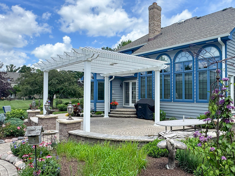 freestanding traditional style white shade pergola on a patio surrounded by a lovely garden