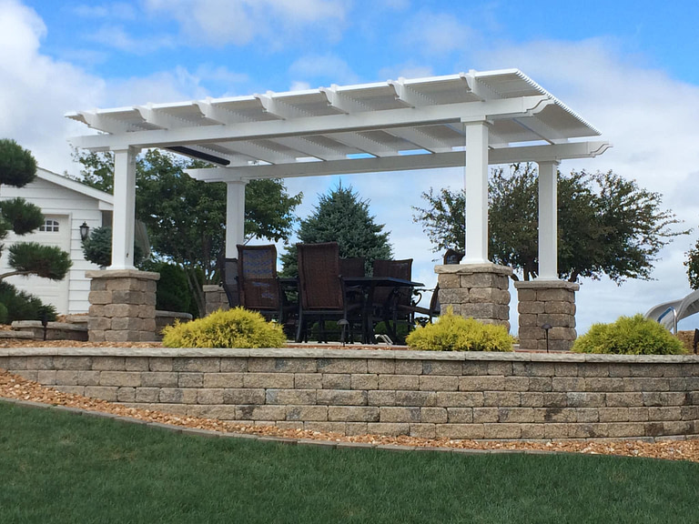 White pergola on top of decorative stone columns