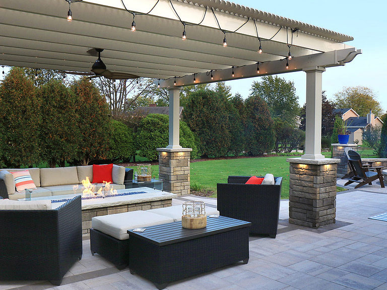 Vinyl pergola over outdoor seating area and fire pit with lights and stone columns