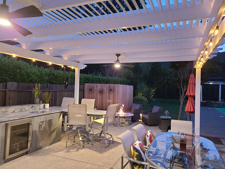 View under pergola on a patio with outdoor fan at dusk