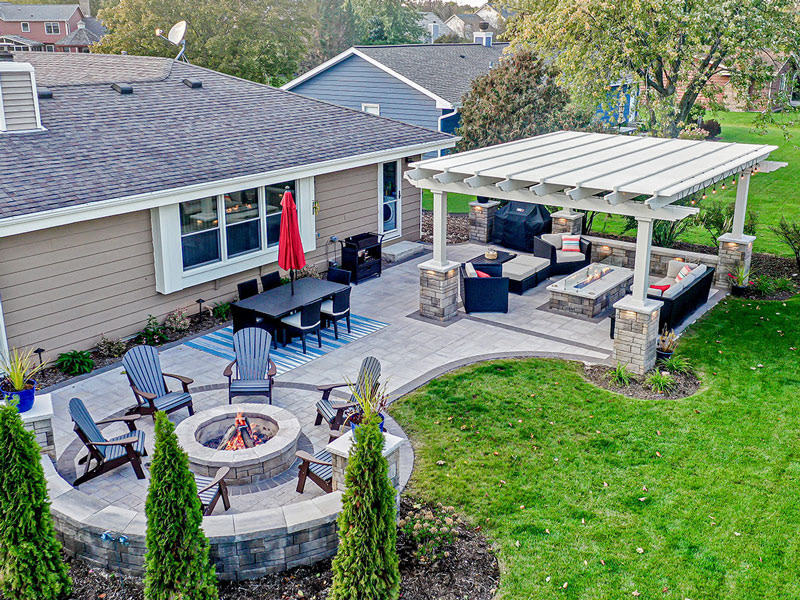 nicely landscaped backyard with fire pit and outdoor seating area under a freestanding pergola