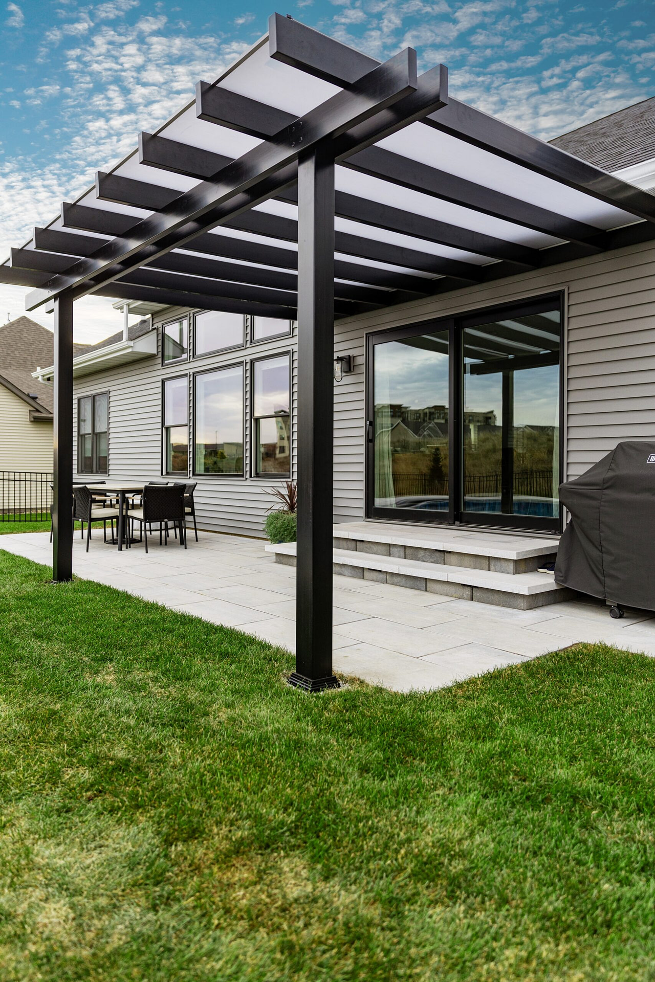 Black patio cover with white polycarbonate roof over a patio
