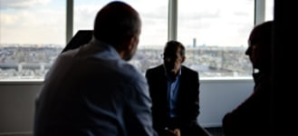 group of businesspeople sitting inside office with skyline in background