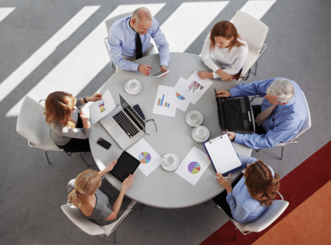 Mask Group 57 team of 6 business persons working together at a circular table