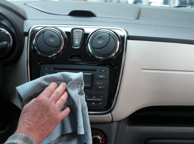 person cleaning automobile radio with rag