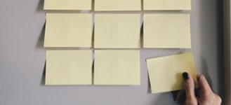 Blank, yellow post-it notes being placed on a wall.