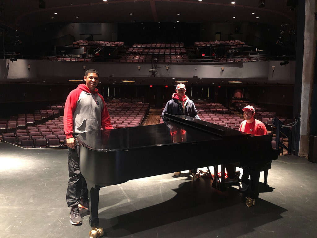 movers posing with a grand piano