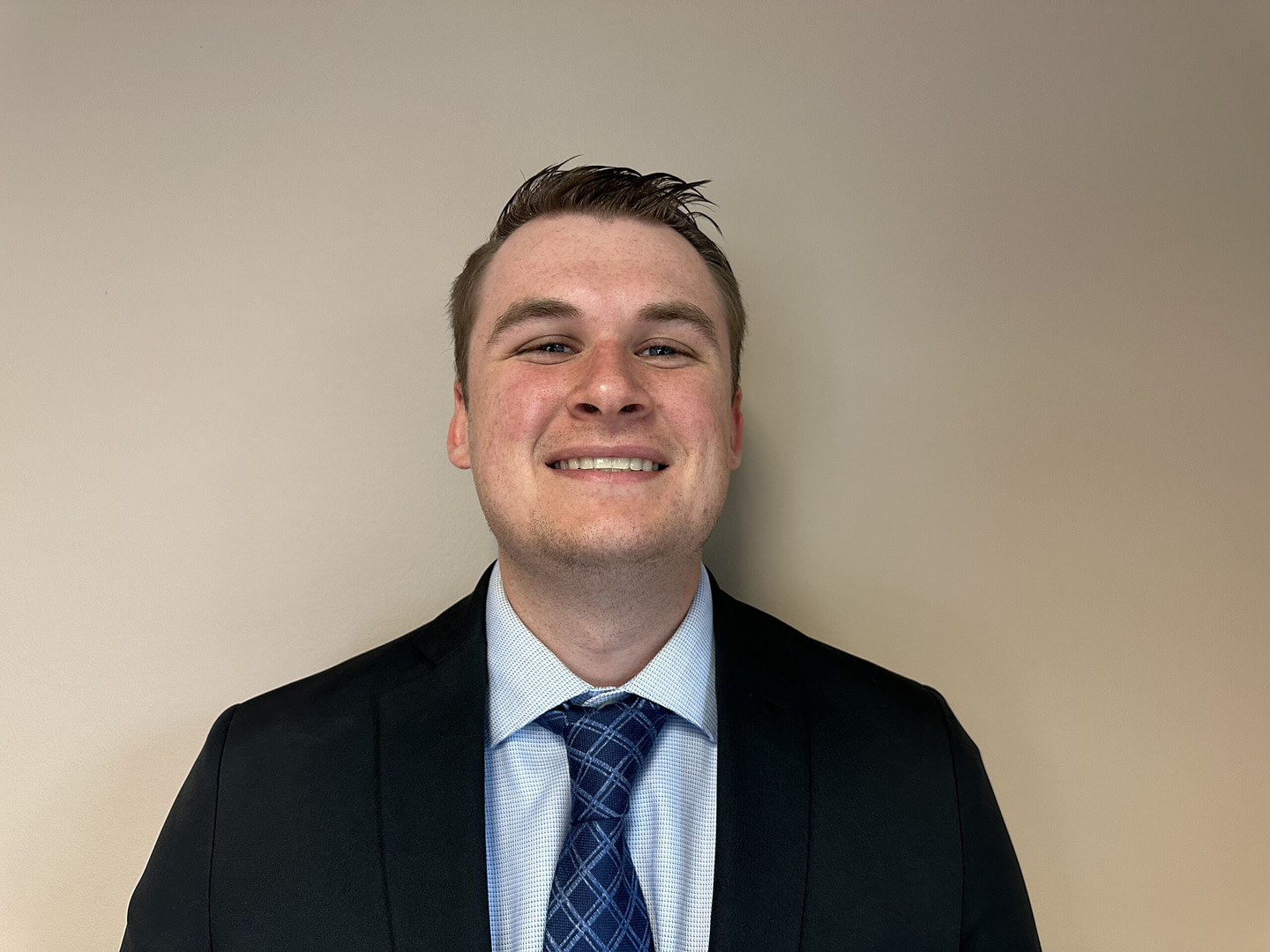 Smiling businessman in suit and tie against beige wall