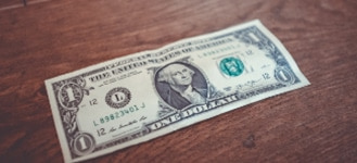 single dollar bill atop wooden table