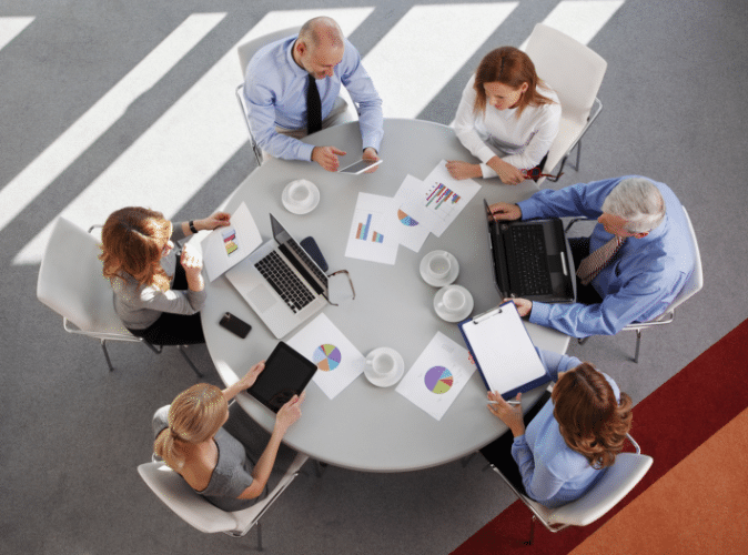 team of 6 business persons working together at a circular table