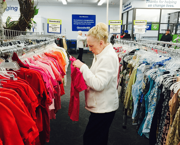 woman looking at shirt in Goodwill